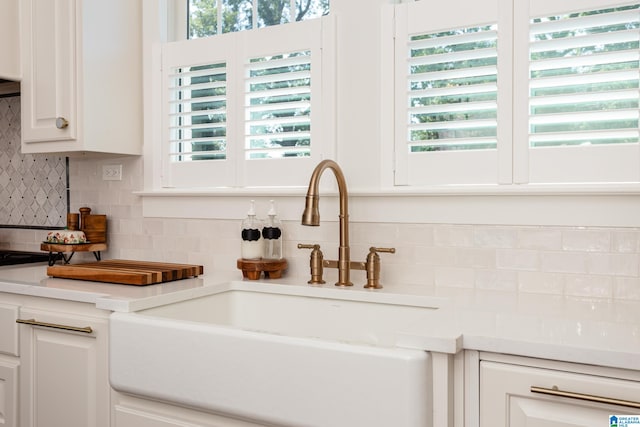 interior space featuring white cabinets, sink, and decorative backsplash