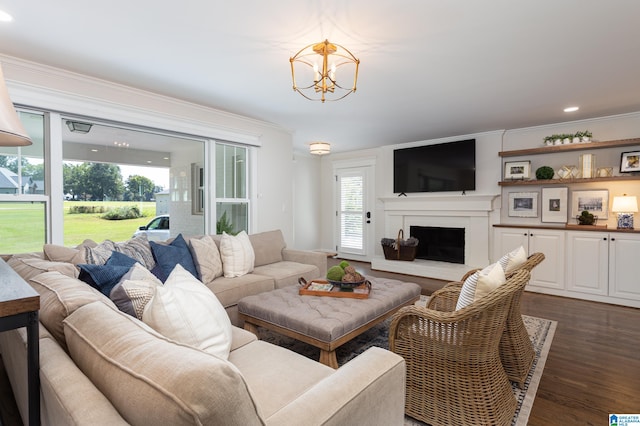 living room featuring crown molding, dark wood-type flooring, and an inviting chandelier