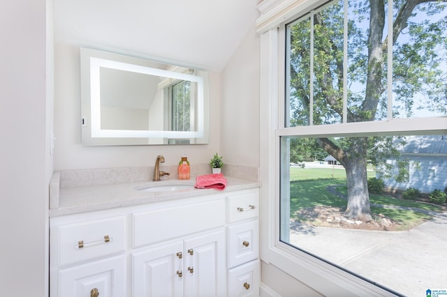 bathroom with a wealth of natural light, vanity, and lofted ceiling