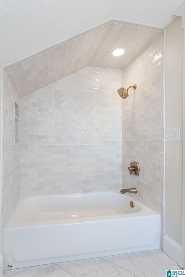 bathroom with lofted ceiling and tiled shower / bath combo