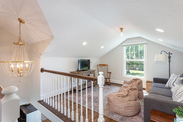 interior space with a textured ceiling, vaulted ceiling, an inviting chandelier, and hardwood / wood-style floors