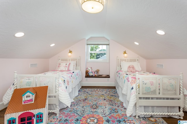 bedroom featuring hardwood / wood-style floors, a textured ceiling, and vaulted ceiling