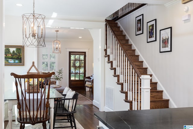 dining area featuring dark wood-type flooring, crown molding, and a notable chandelier