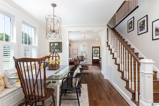 dining area with dark wood-type flooring, ornamental molding, and a chandelier