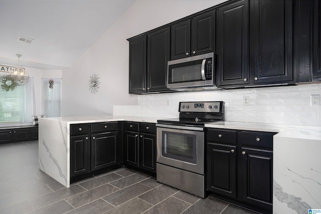 kitchen with pendant lighting, a chandelier, lofted ceiling, backsplash, and appliances with stainless steel finishes