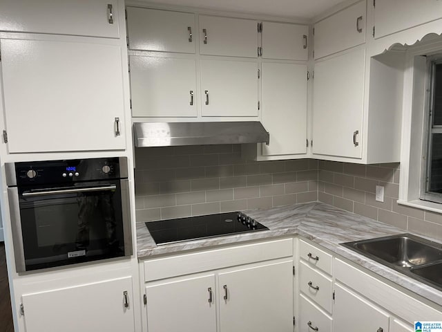 kitchen with white cabinets, black electric stovetop, stainless steel oven, and decorative backsplash