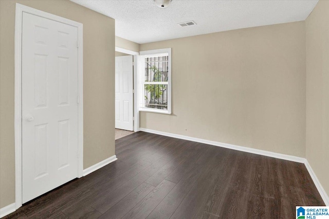 empty room with a textured ceiling and dark wood-type flooring