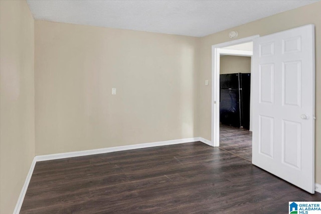 empty room featuring a textured ceiling and dark hardwood / wood-style flooring