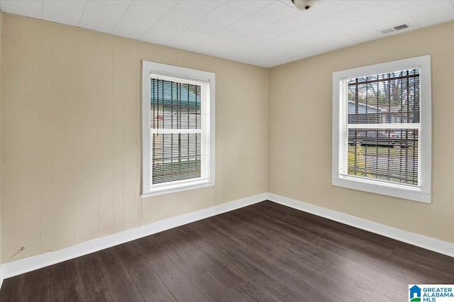 empty room with wood-type flooring and wooden walls