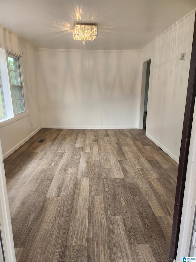 unfurnished room featuring an inviting chandelier and hardwood / wood-style flooring