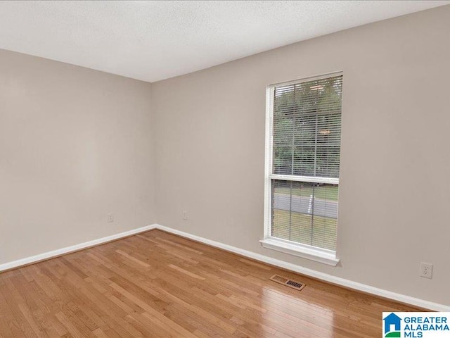 spare room with a textured ceiling and light hardwood / wood-style flooring