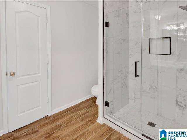 bathroom with hardwood / wood-style floors, walk in shower, and toilet