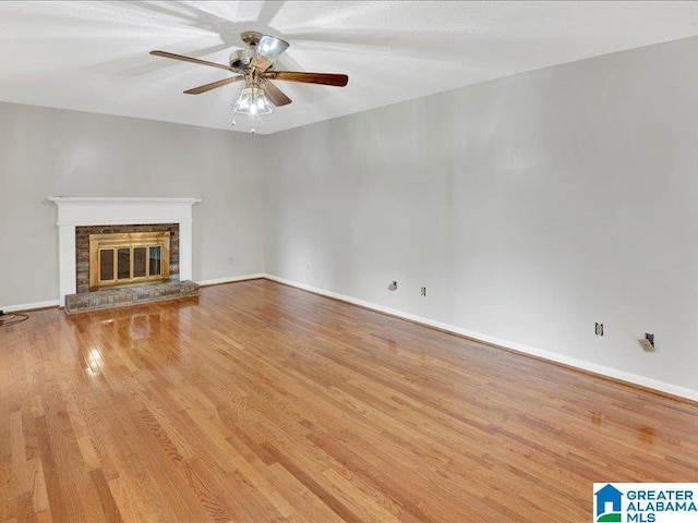 unfurnished living room featuring ceiling fan, a brick fireplace, and light hardwood / wood-style floors