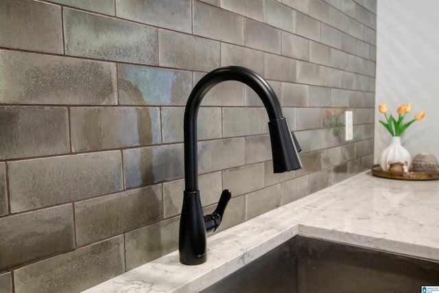room details with light stone counters, tasteful backsplash, and a sink