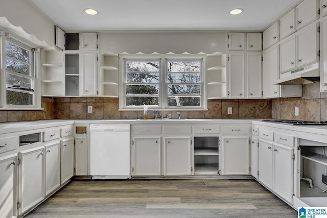 kitchen with light wood-type flooring, tasteful backsplash, white dishwasher, stainless steel gas cooktop, and white cabinetry