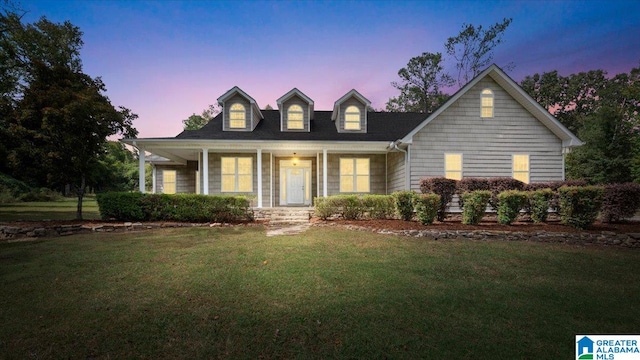 cape cod-style house with a yard and covered porch