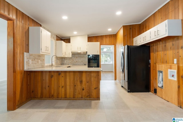 kitchen featuring wooden walls, ornamental molding, black appliances, white cabinets, and kitchen peninsula