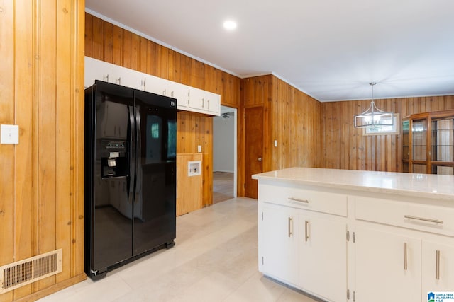 kitchen featuring wood walls, a chandelier, black refrigerator with ice dispenser, pendant lighting, and white cabinets