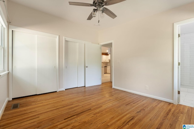 unfurnished bedroom with multiple closets, ceiling fan, ensuite bath, and light hardwood / wood-style flooring