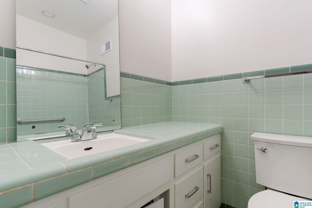 bathroom with vanity, toilet, tile walls, and a shower