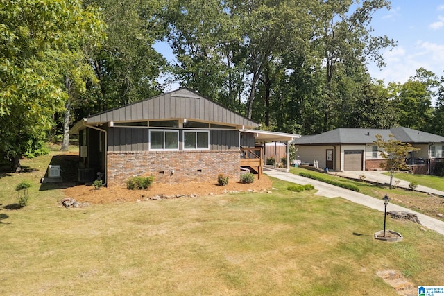 view of front of property featuring a carport, a garage, central AC unit, and a front lawn