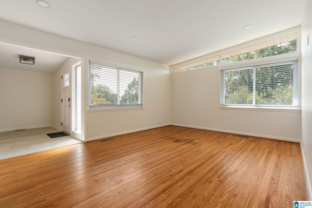 empty room with lofted ceiling and light wood-type flooring