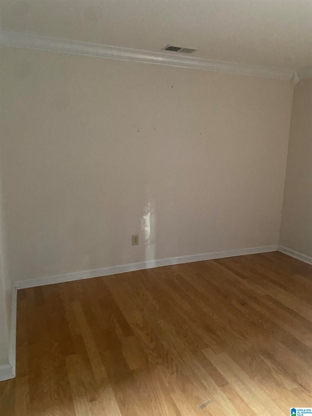 empty room featuring ornamental molding and hardwood / wood-style floors