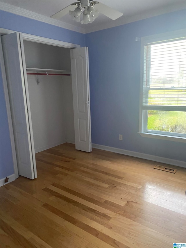 unfurnished bedroom featuring ceiling fan, ornamental molding, a closet, and light wood-type flooring