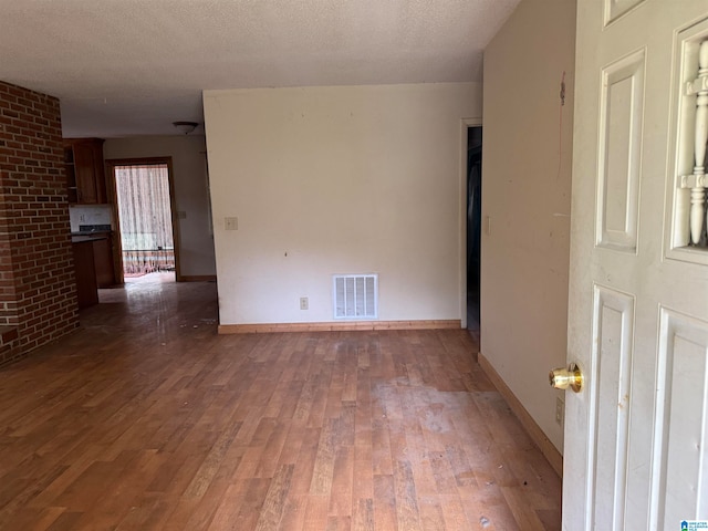 empty room with dark wood-type flooring and a textured ceiling