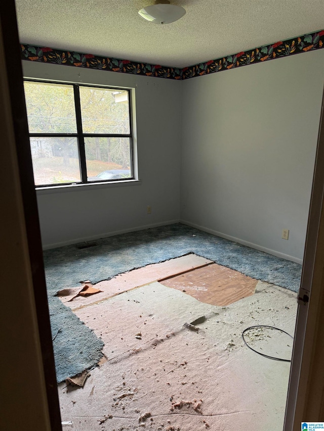 unfurnished room with a textured ceiling