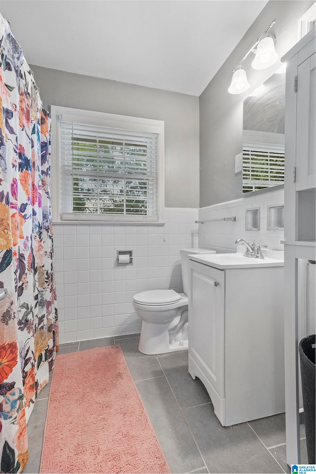 bathroom with vanity, curtained shower, tile walls, toilet, and tile patterned floors