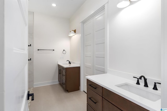 full bath featuring a sink, two vanities, recessed lighting, and baseboards