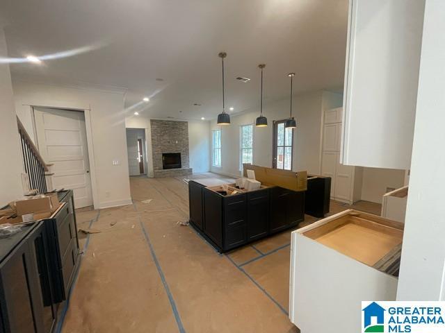 kitchen featuring a fireplace, a center island, dark cabinetry, and hanging light fixtures