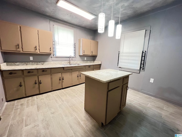 kitchen with a kitchen island, sink, decorative light fixtures, and light hardwood / wood-style floors