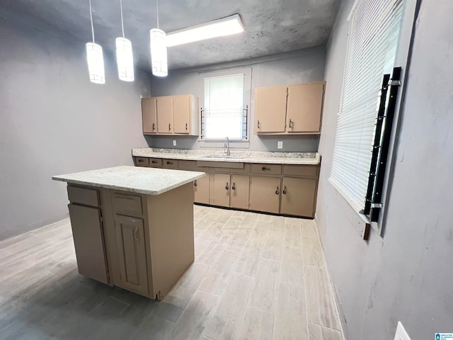 kitchen with light brown cabinetry, hanging light fixtures, a center island, sink, and light wood-type flooring