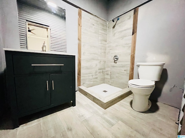 bathroom with tiled shower, toilet, and vanity