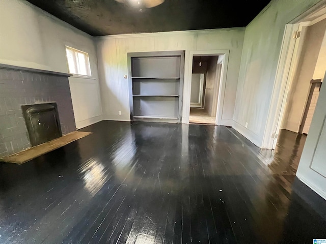 unfurnished living room featuring built in features, a fireplace, and dark hardwood / wood-style floors