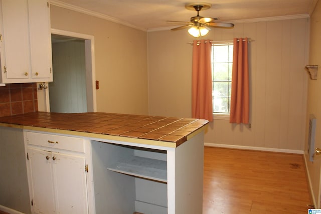 kitchen featuring ornamental molding, white cabinetry, light hardwood / wood-style flooring, tile counters, and ceiling fan