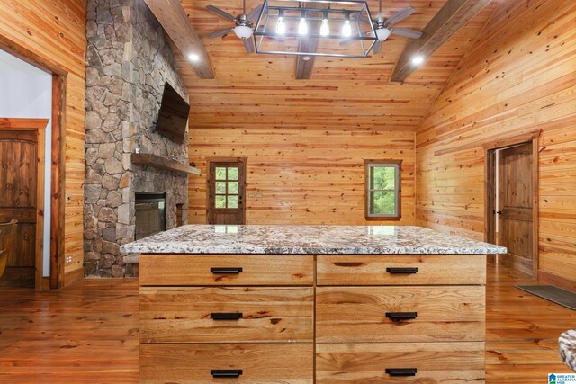 kitchen with beamed ceiling, light hardwood / wood-style flooring, wood walls, and ceiling fan