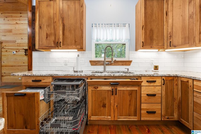 kitchen with dark wood-type flooring, light stone counters, decorative backsplash, and sink