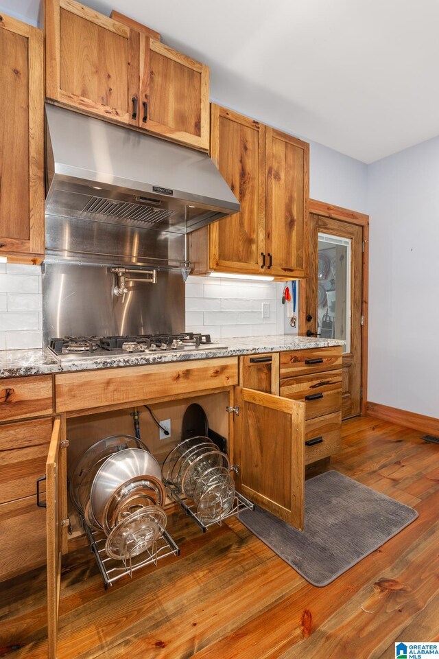 kitchen featuring backsplash, light stone counters, dark hardwood / wood-style flooring, and stainless steel gas stovetop