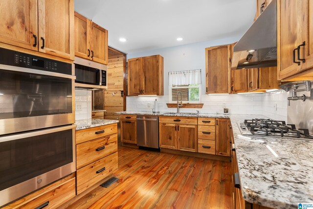 kitchen featuring tasteful backsplash, dark hardwood / wood-style flooring, sink, light stone countertops, and appliances with stainless steel finishes