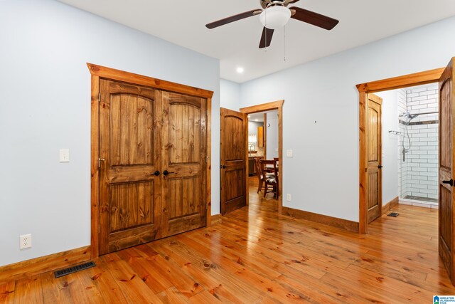 bedroom with light hardwood / wood-style flooring, ensuite bath, and ceiling fan