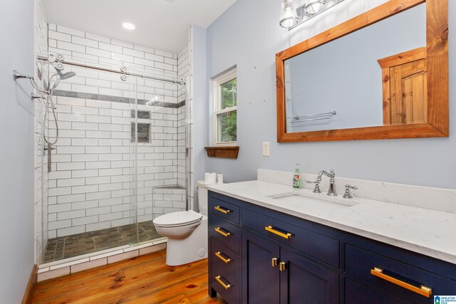 bathroom featuring vanity, toilet, hardwood / wood-style floors, and walk in shower