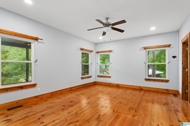 empty room with ceiling fan, plenty of natural light, and light hardwood / wood-style floors