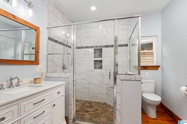 bathroom featuring an enclosed shower, wood-type flooring, toilet, and vanity