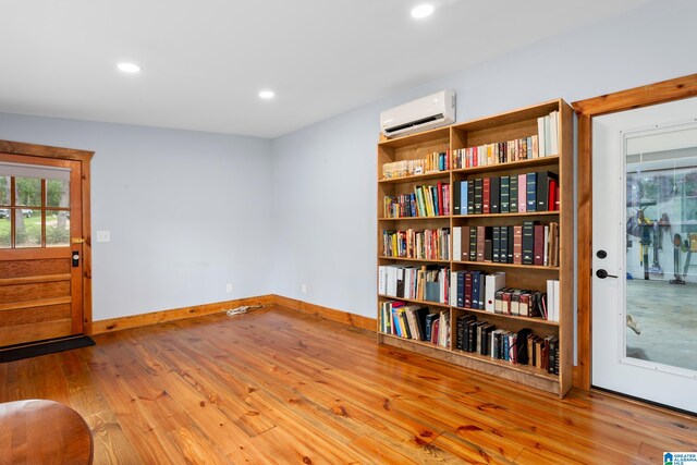 sitting room with light hardwood / wood-style flooring and a wall unit AC