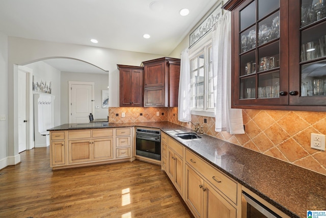 kitchen featuring tasteful backsplash, dark hardwood / wood-style flooring, oven, beverage cooler, and sink