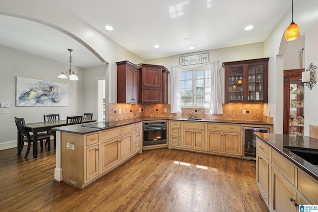 kitchen featuring black appliances, dark hardwood / wood-style flooring, wine cooler, and decorative light fixtures