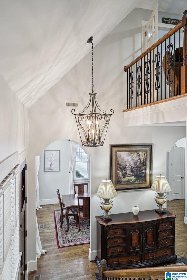 interior space with wood-type flooring, an inviting chandelier, and high vaulted ceiling